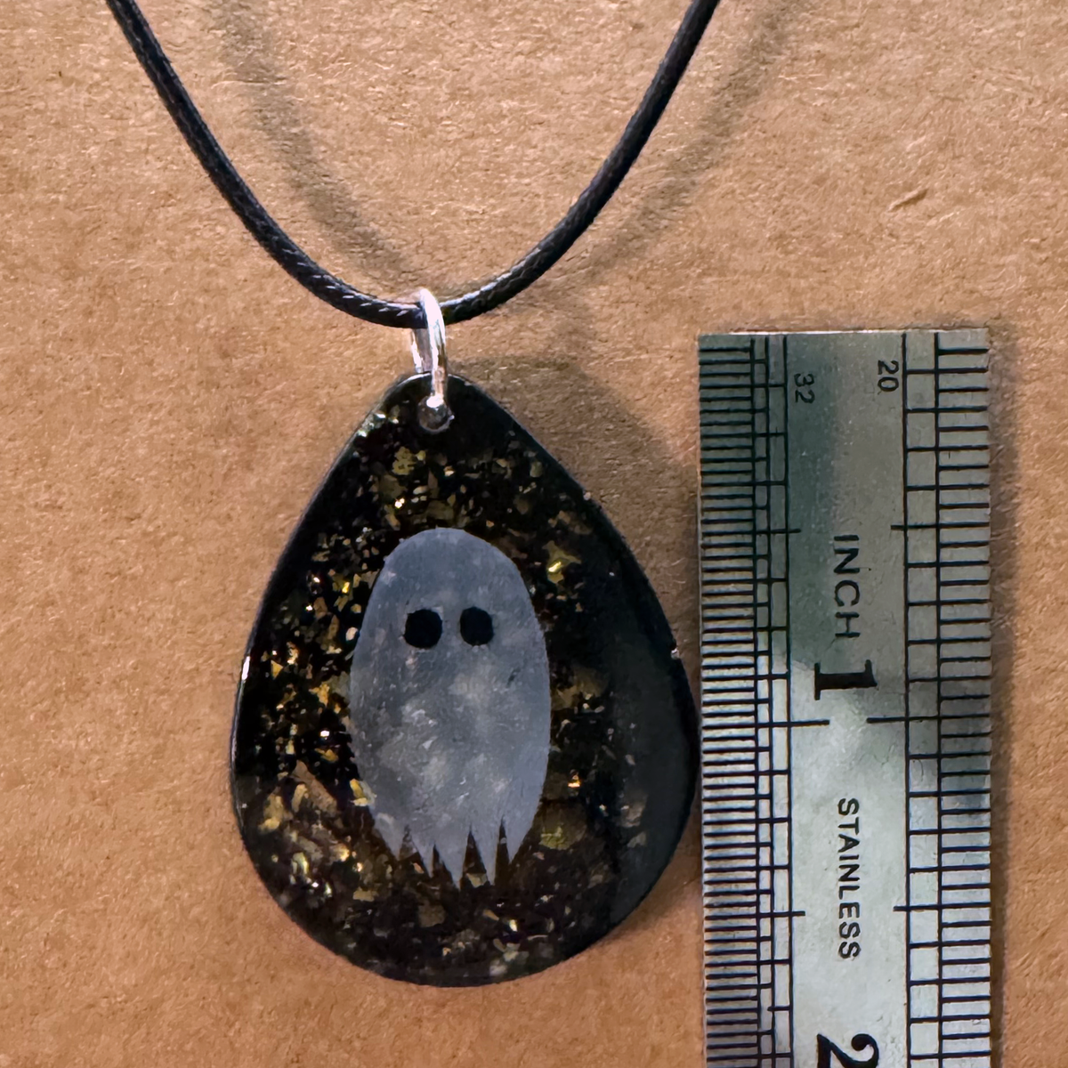 Necklace - A Teardrop Shaped Resin Charm Features A Paper Ghost Floating on A Sparkly Black Background