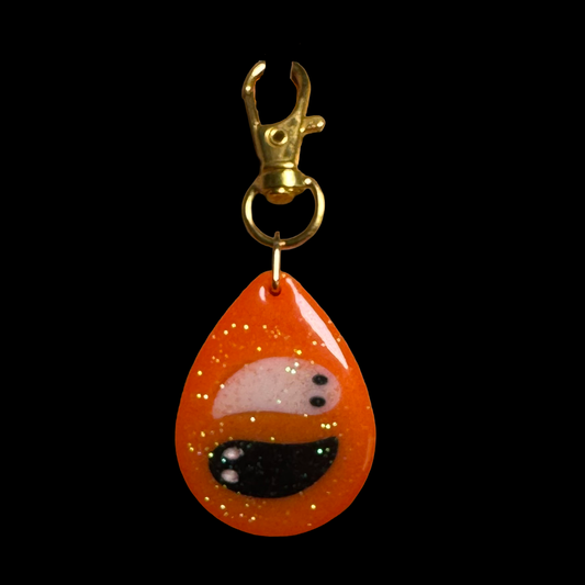 Resin Charm - 2 Ghosts float on a Sparkly Orange Background that Glows in the Dark