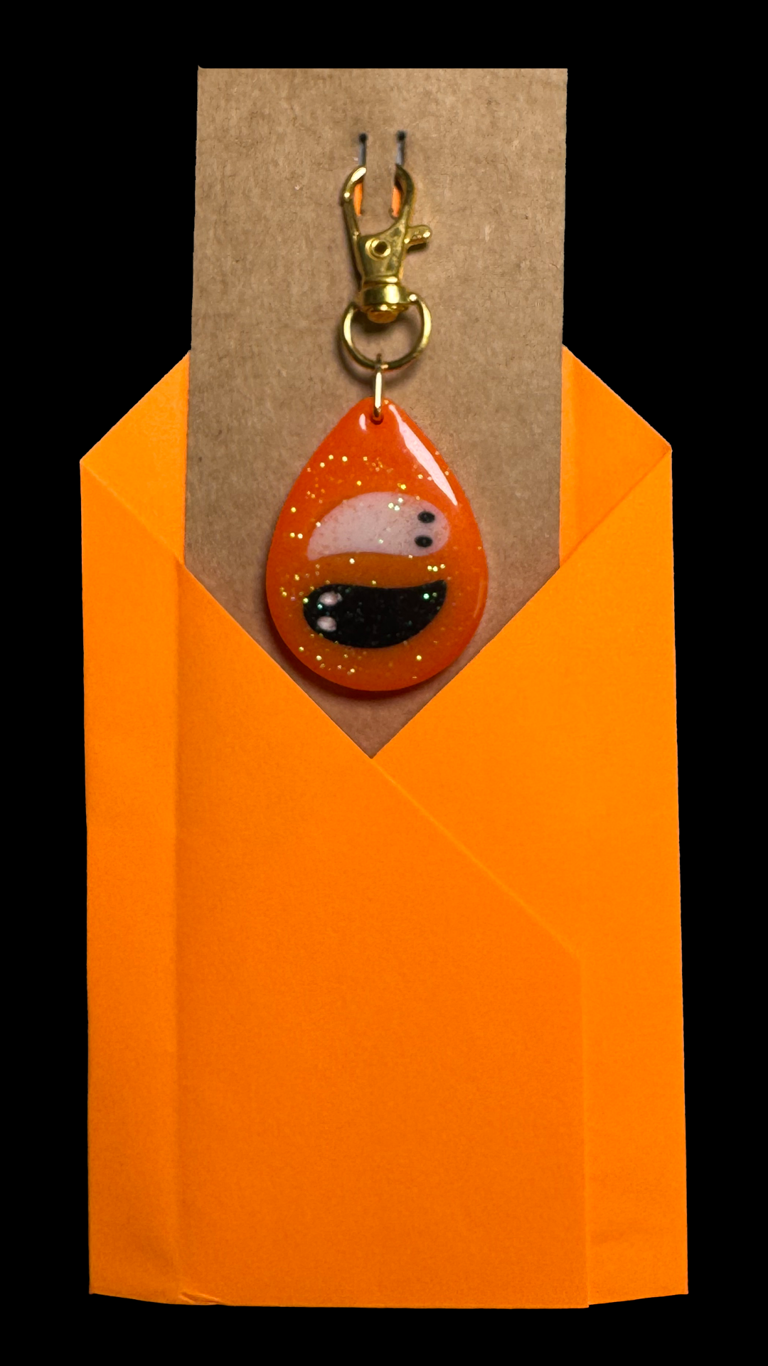 Resin Charm - 2 Ghosts float on a Sparkly Orange Background that Glows in the Dark